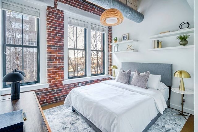 a bedroom with a bed lamp and a large window with the outer view