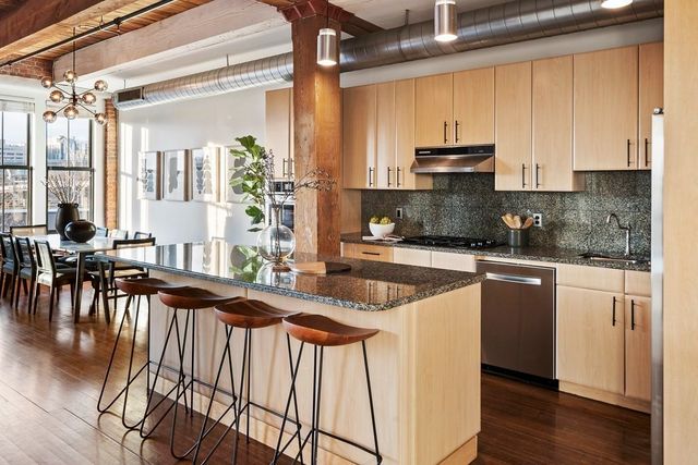 a kitchen with stainless steel appliances granite countertop a stove a sink and white cabinets with wooden floor