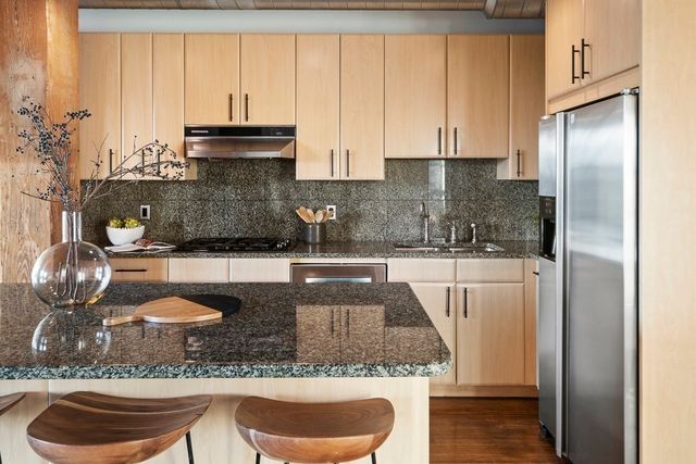 a kitchen with granite countertop a refrigerator a stove and a sink