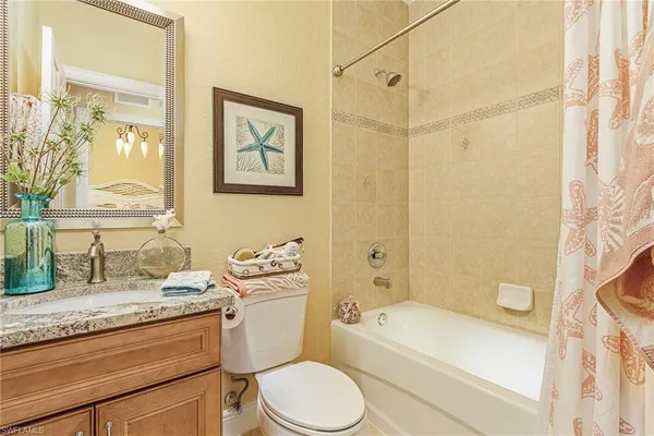 a bathroom with a granite countertop toilet sink and mirror