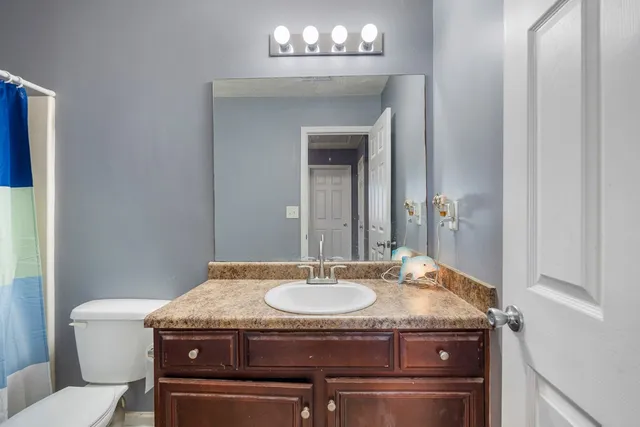 a bathroom with a granite countertop sink a toilet and a mirror