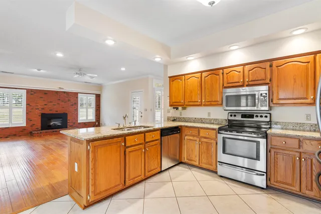 a kitchen with stainless steel appliances granite countertop a stove top oven a sink dishwasher a dining table and chairs with wooden floor