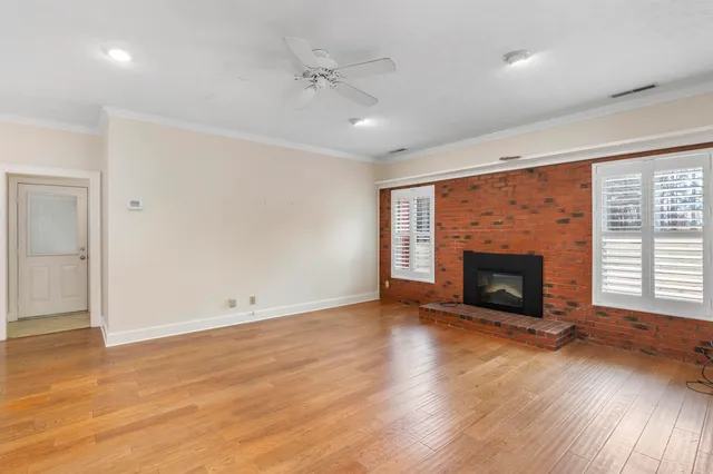 an empty room with wooden floor fireplace and windows