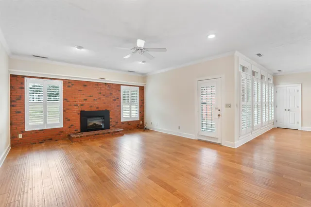 a view of an empty room with wooden floor fireplace and a window