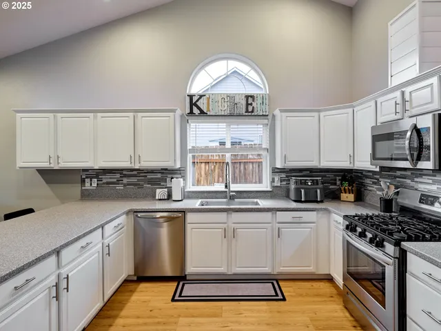 a kitchen with a sink white cabinets and stainless steel appliances