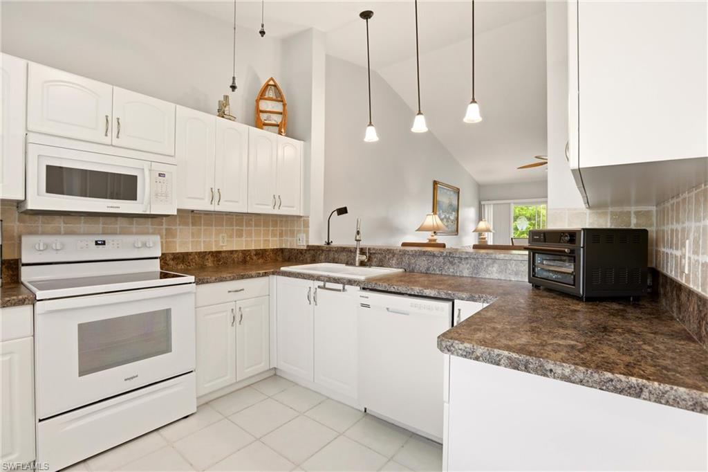 1723 Reuven Circle, Unit 2004 Naples, FL 34112 - Photo 7 of 29 a kitchen with stainless steel appliances granite countertop a sink a stove and a microwave