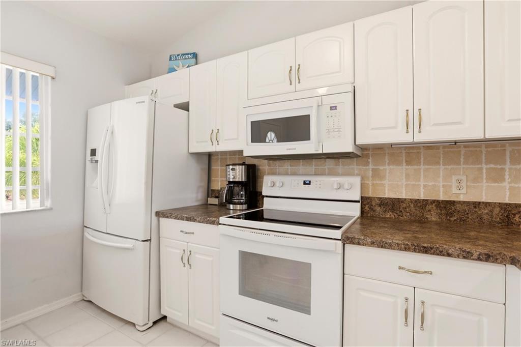 1723 Reuven Circle, Unit 2004 Naples, FL 34112 - Photo 9 of 29 a kitchen with white cabinets and white appliances