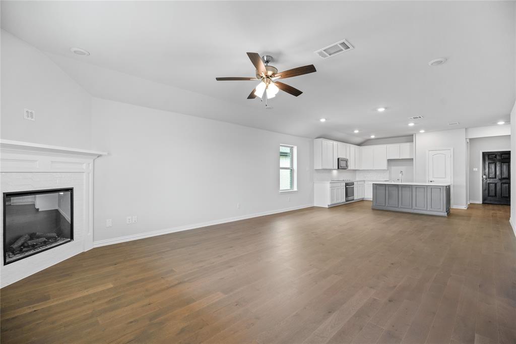 2608 Freeman Street Anna, TX 75409 - Photo 15 of 22 a view of a livingroom with a fireplace a ceiling fan and wooden floor