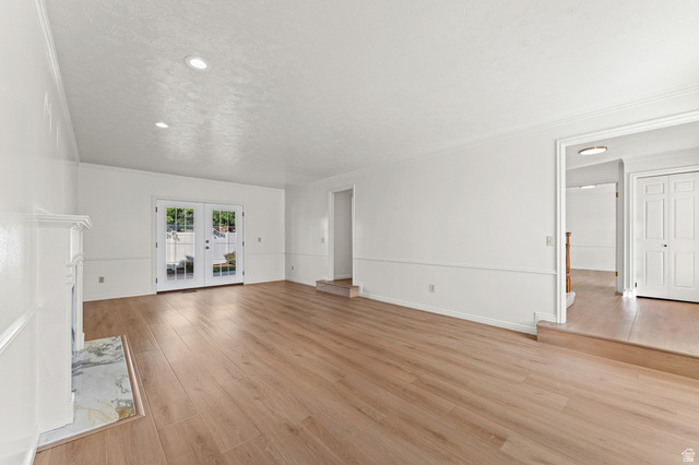 8441 Rua Branco Drive Sandy, UT 84093 - Photo 7 of 47 Spacious primary living area showcasing gleaming wood-finish flooring throughout, crisp white walls, and abundant natural light from dual French doors