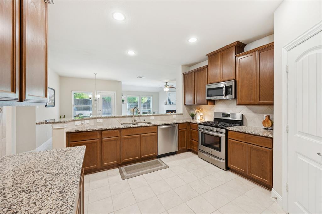 4017 Netherfield Road Frisco, TX 75036 - Photo 10 of 29 a kitchen with stainless steel appliances granite countertop a stove top oven a sink dishwasher a dining table and chairs with wooden floor