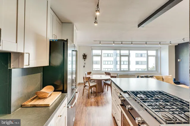 a kitchen with stainless steel appliances granite countertop a stove top oven a sink dishwasher and white cabinets with wooden floor