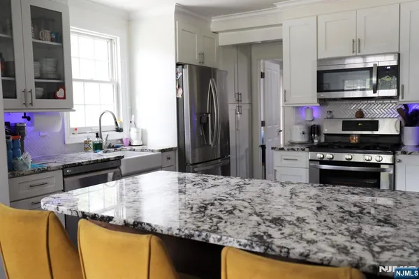 a kitchen with kitchen island granite countertop a sink stove and refrigerator