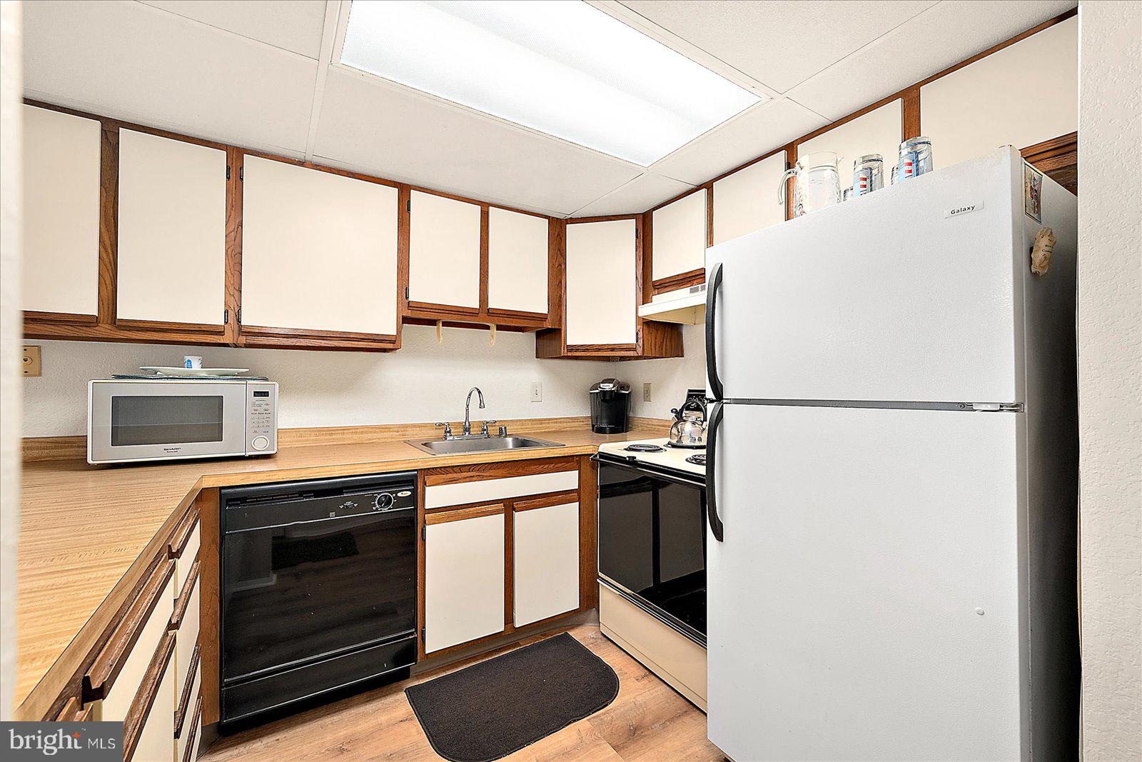 5801 Atlantic Avenue, Unit 101 Ocean City, MD 21842 - Photo 13 of 50 a kitchen with stainless steel appliances a refrigerator sink and cabinets