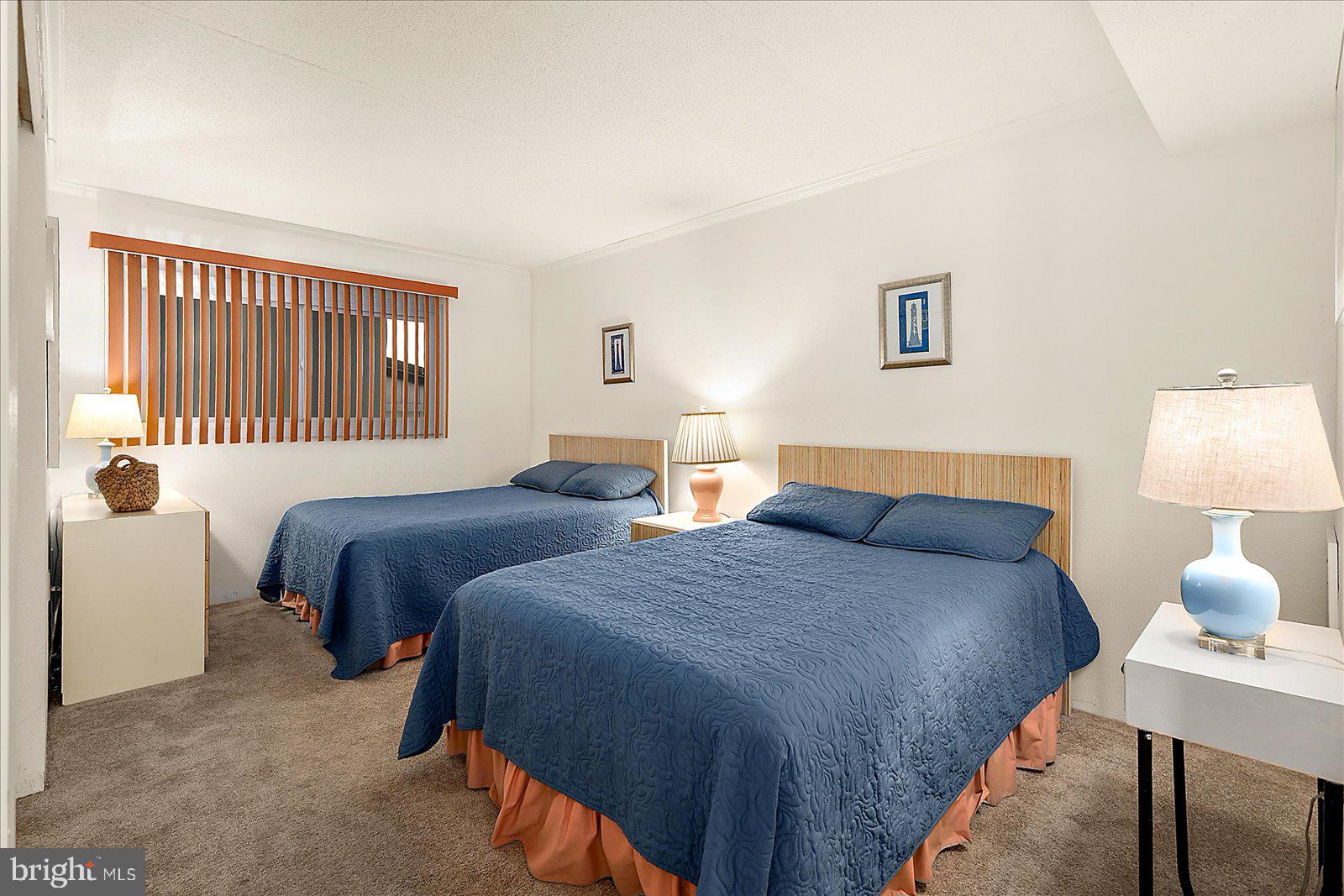 5801 Atlantic Avenue, Unit 101 Ocean City, MD 21842 - Photo 23 of 50 a bedroom with two beds and a lamp on the dresser