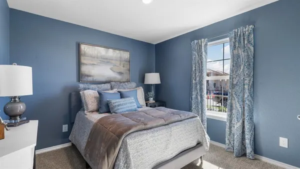 a bedroom with a bed and a window with chair