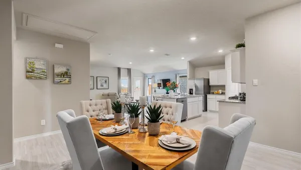 a dining room with furniture a wooden floor and kitchen view