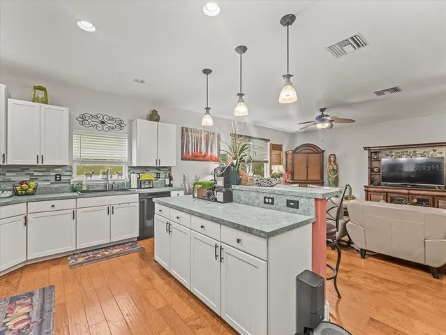 a living room with furniture kitchen view and a large window