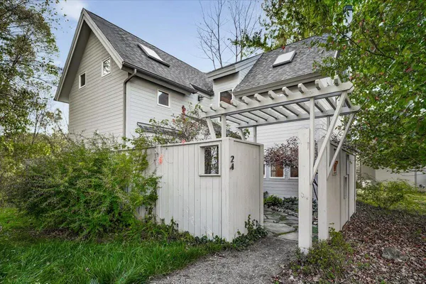 a view of a white house next to a yard with large trees