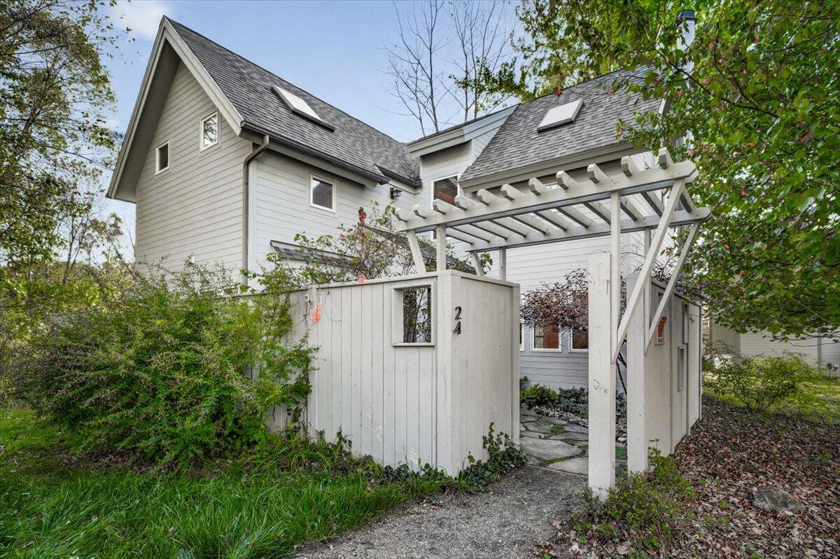a view of a white house next to a yard with large trees