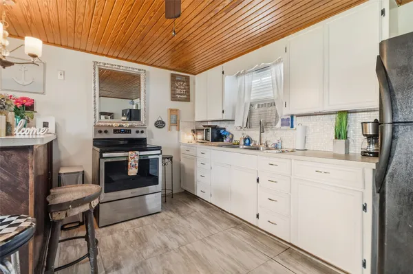 a kitchen with granite countertop a sink cabinets stainless steel appliances and a window