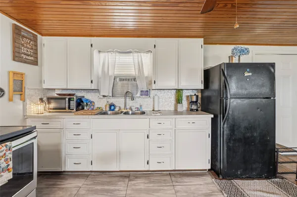 a kitchen with white cabinets and refrigerator
