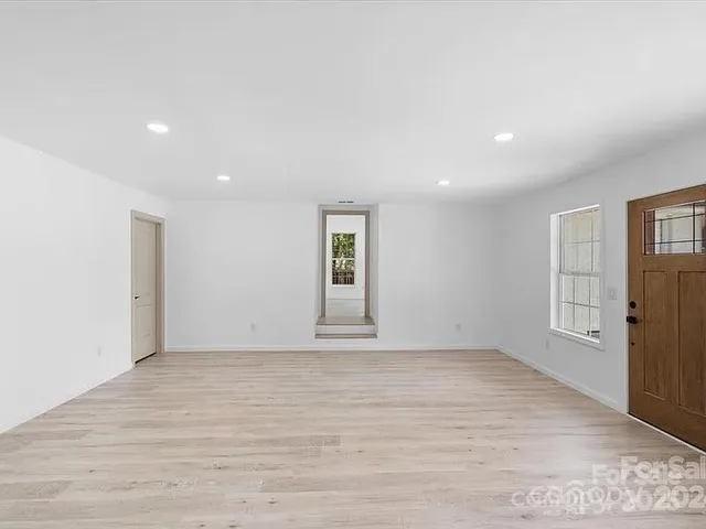 a view of an empty room with window and wooden floor