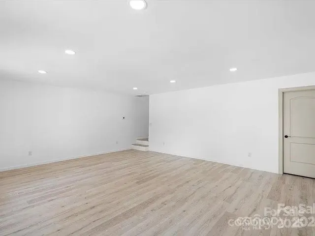 an empty room with wooden floor and white walls
