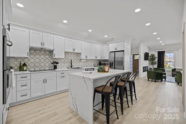 a kitchen with stainless steel appliances granite countertop a table chairs sink refrigerator and cabinets
