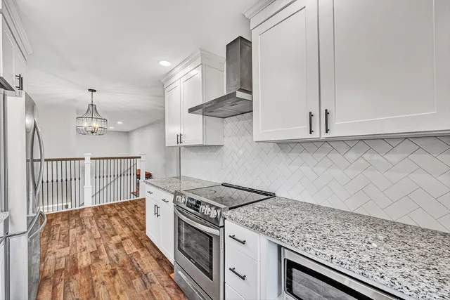 a kitchen with stainless steel appliances granite countertop a stove and a white cabinets