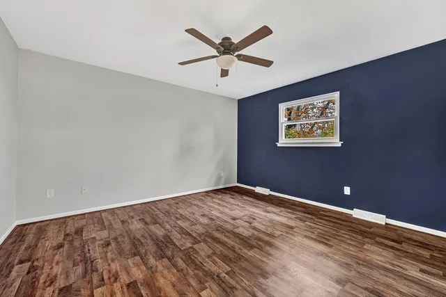 an empty room with window and ceiling fan