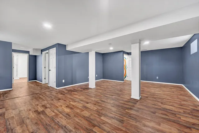 a view of an empty room with wooden floor and window