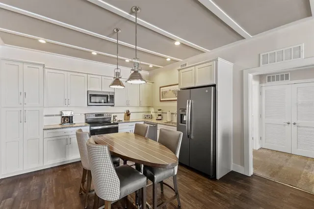 a kitchen with stainless steel appliances a dining table chairs refrigerator and microwave