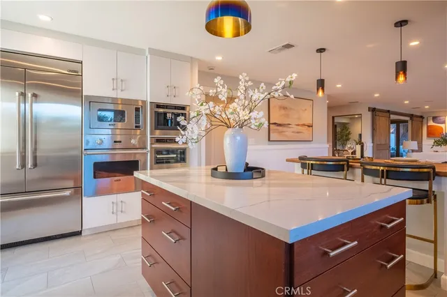 a kitchen with kitchen island granite countertop a refrigerator and a sink
