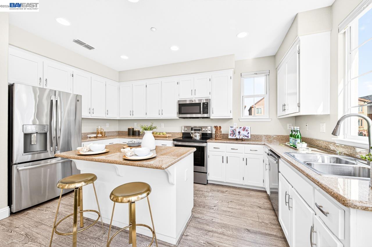 2871 First Street, Unit 901 Livermore, CA 94550 - Photo 14 of 46 a kitchen with stainless steel appliances granite countertop a stove a sink dishwasher a refrigerator and a microwave with wooden floor