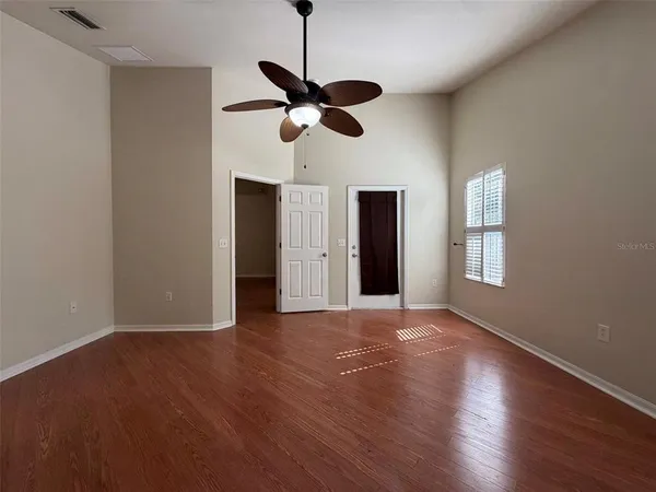 a view of empty room with wooden floor and ceiling fan