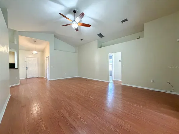 a view of empty room with wooden floor and fan