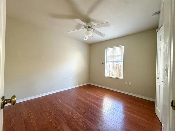 an empty room with wooden floor fan and windows