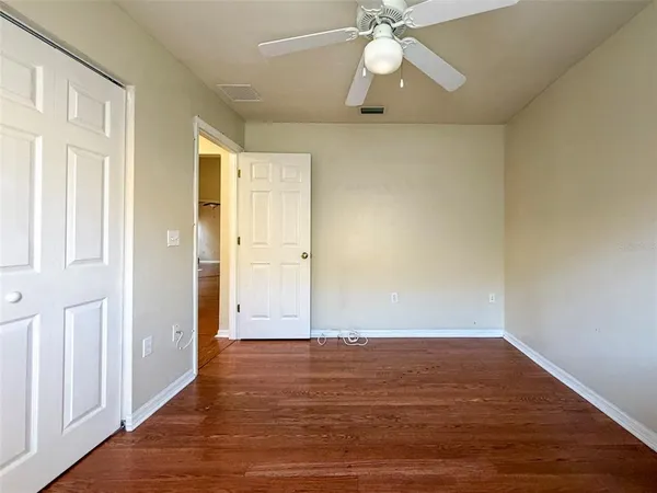 an empty room with wooden floor fan and windows