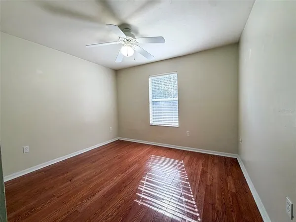 an empty room with wooden floor chandelier fan and window