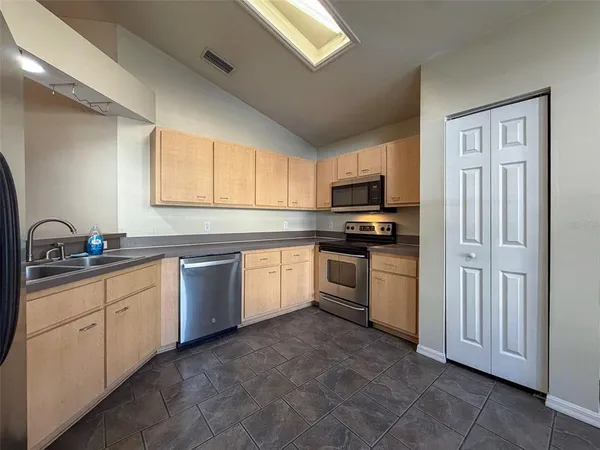a kitchen with granite countertop a sink stainless steel appliances and window