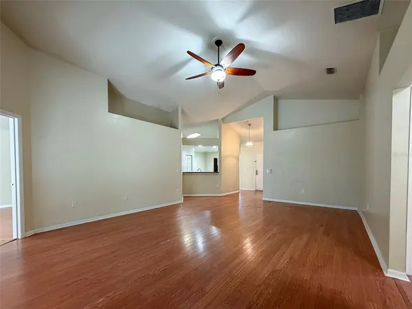 an empty room with wooden floor fan and windows