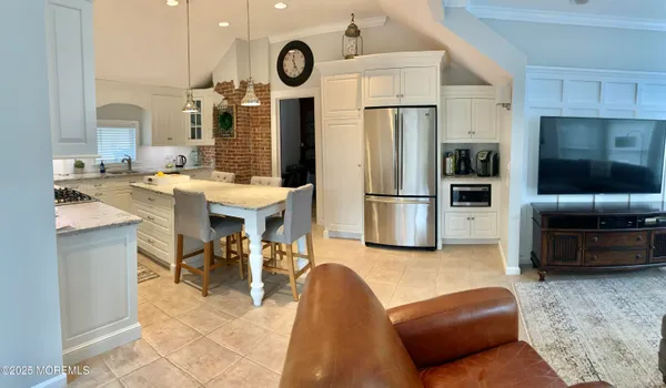 a living room with stainless steel appliances furniture a rug and a kitchen view
