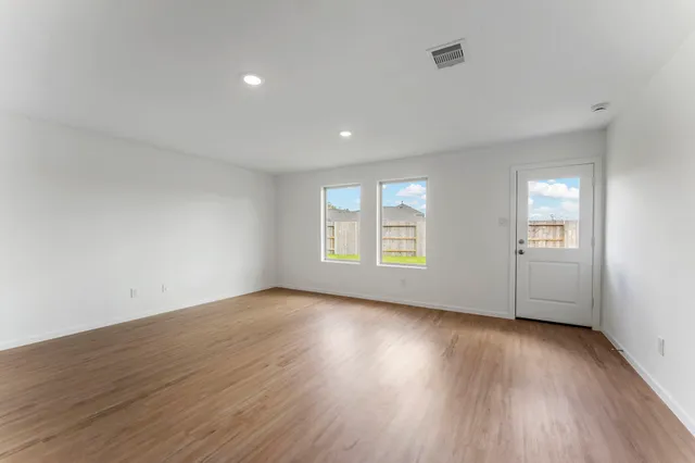 a view of an empty room with wooden floor and a window