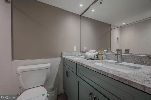 a bathroom with a granite countertop toilet sink and mirror