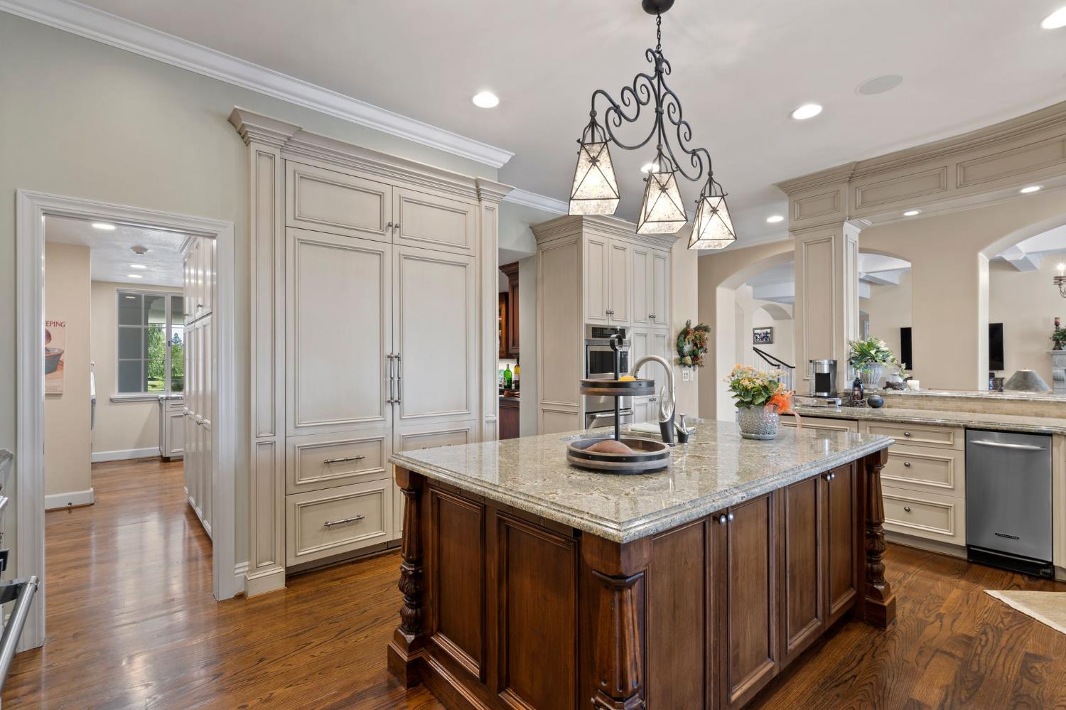 10676 Wilton Road Elk Grove, CA 95624 - Photo 26 of 71 a kitchen with kitchen island granite countertop a sink cabinets and wooden floor