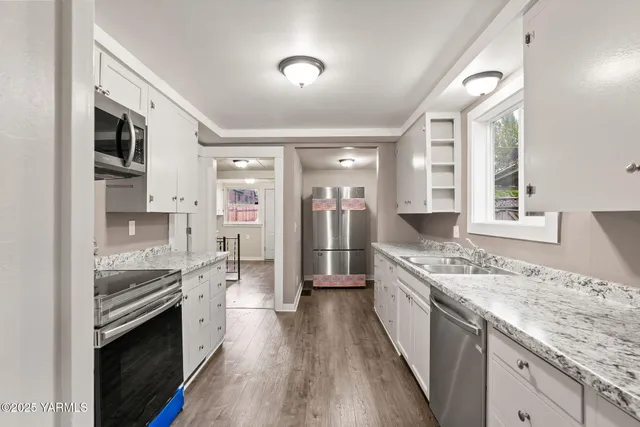 a large kitchen with stainless steel appliances granite countertop a lot of counter space and wooden floor