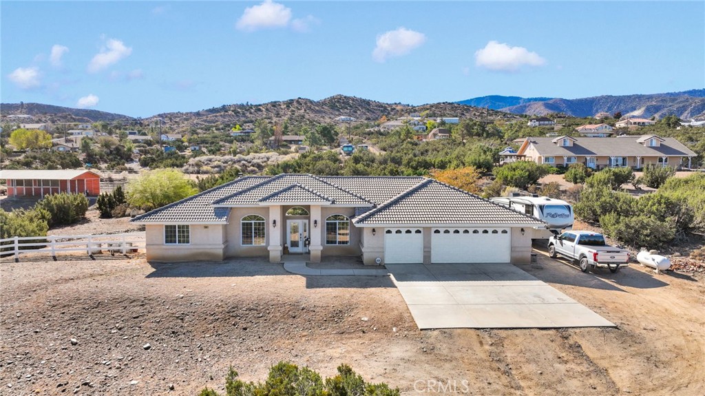 a front view of a house with a yard and mountain view in back