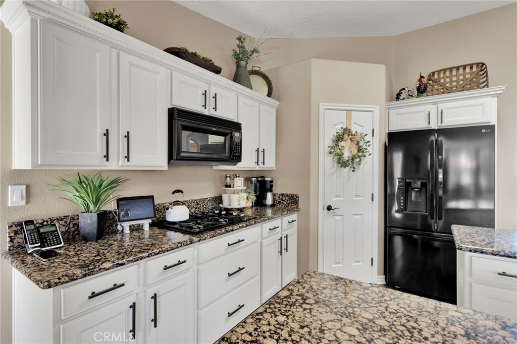 2909 Silver Ridge Drive Pinon Hills, CA 92372 - Photo 13 of 55 a kitchen with stainless steel appliances kitchen island granite countertop a refrigerator a stove a sink dishwasher and white cabinets with wooden floor