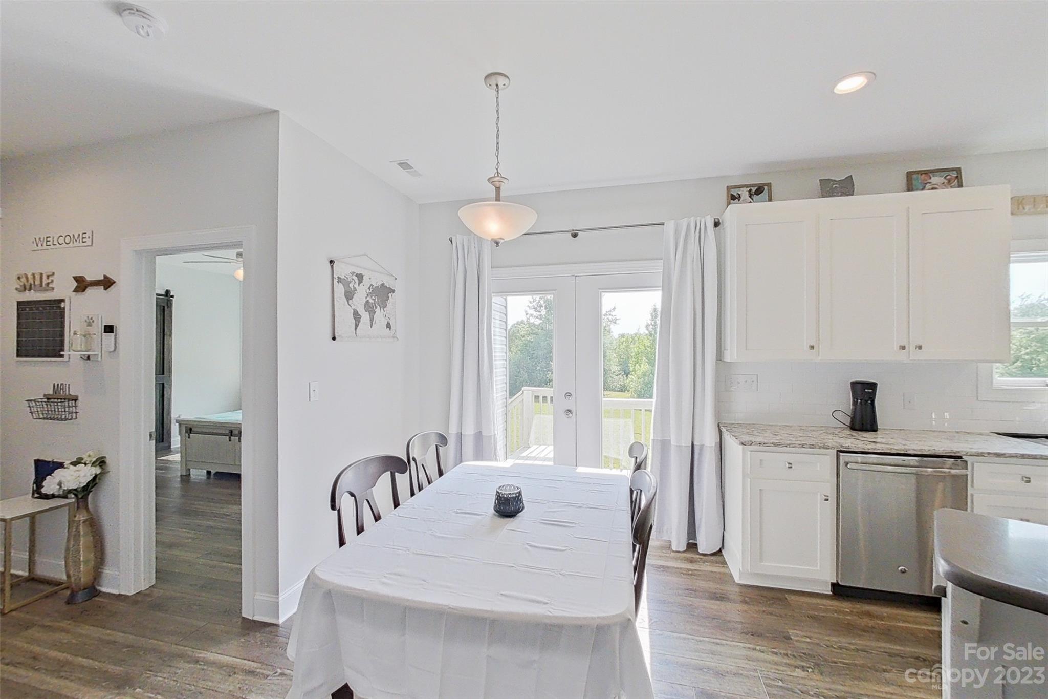 345 Rash Road Olin, NC 28660 - Photo 12 of 39 a large white kitchen with a refrigerator a sink dishwasher a dining table and chairs with wooden floor