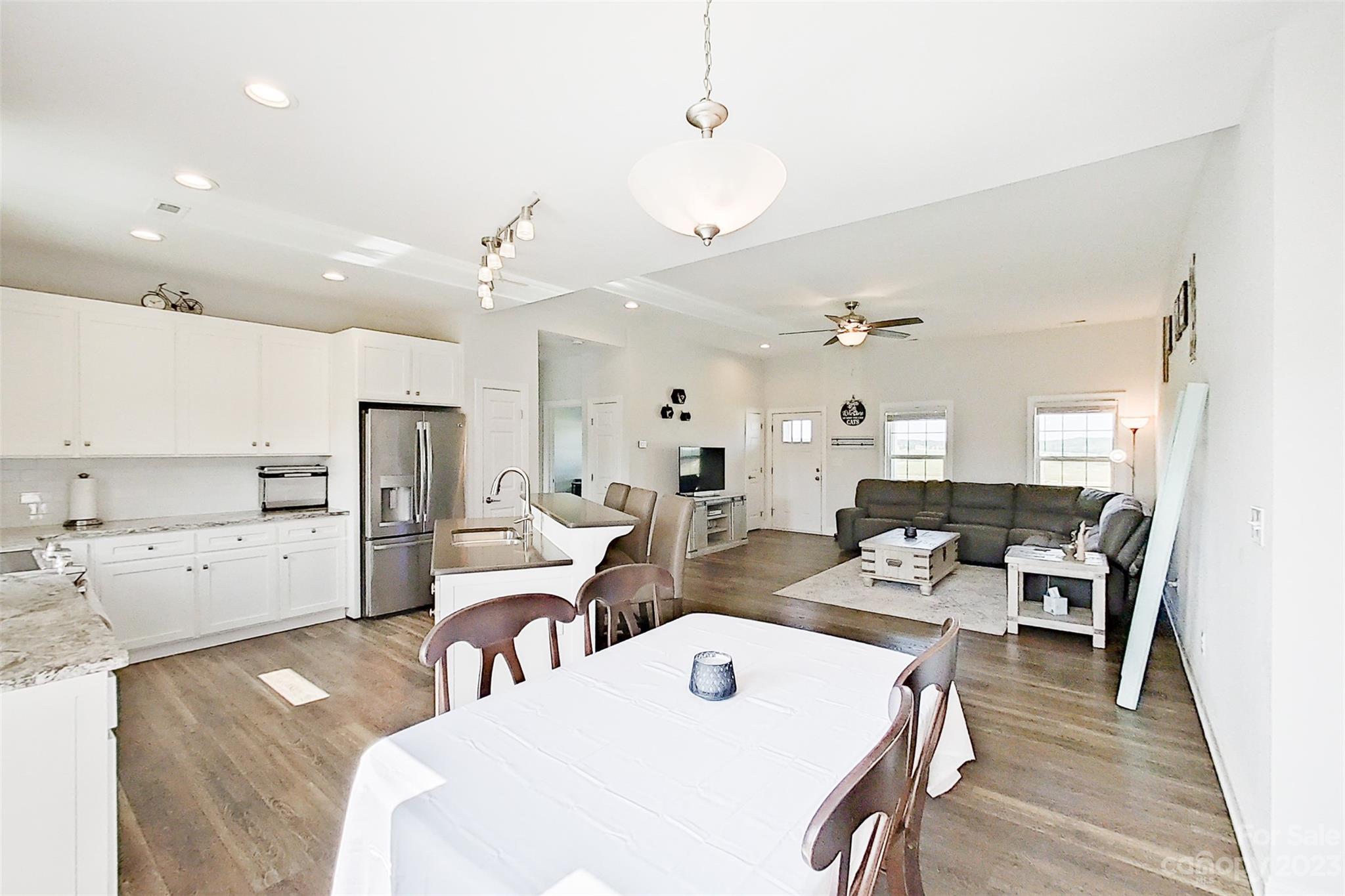 345 Rash Road Olin, NC 28660 - Photo 13 of 39 a large kitchen with kitchen island a stove a sink a refrigerator and white cabinets with wooden floor